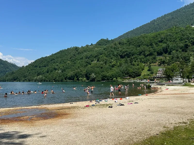 Zwemmers in een meer bij een kiezelstrand