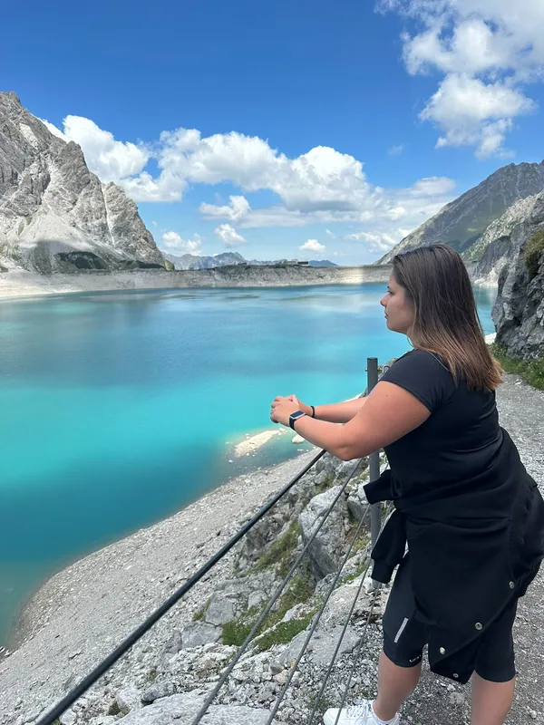 Persoon bij turquoise bergmeer en stalen kabel