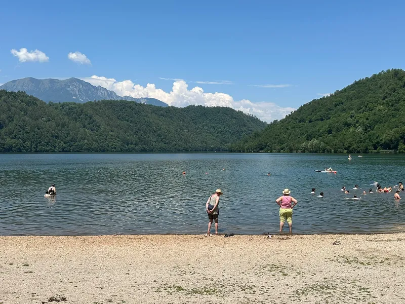 Mensen zwemmen in een bergmeer bij een kiezelstrand