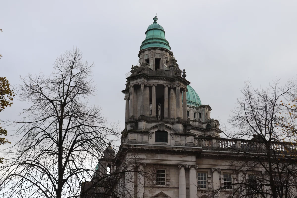 Groene koepels van Belfast City Hall tussen kale herfsttakken