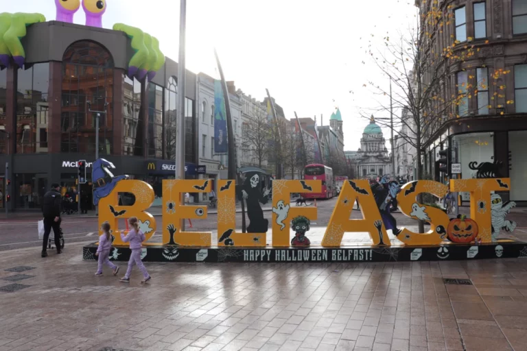 Gele Belfast-letters met Halloweenfiguren en City Hall op de achtergrond