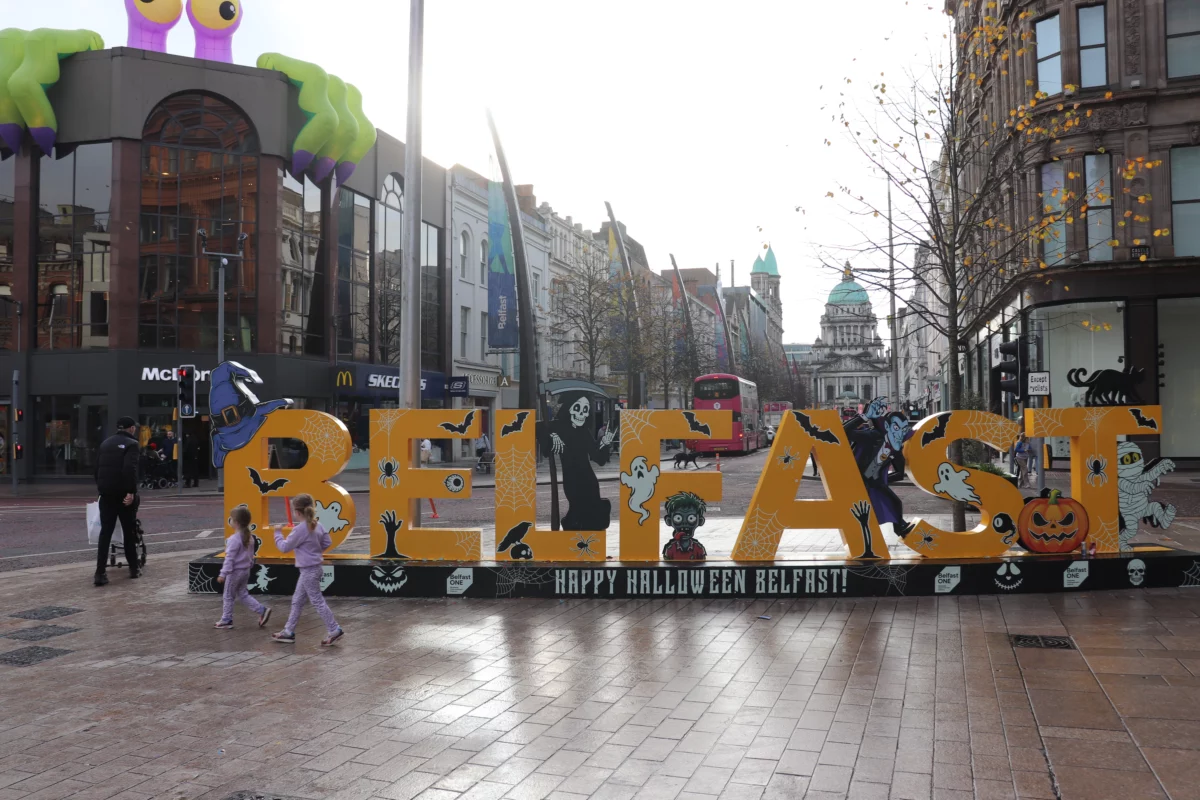 Gele Belfast-letters met Halloweenfiguren en City Hall op de achtergrond