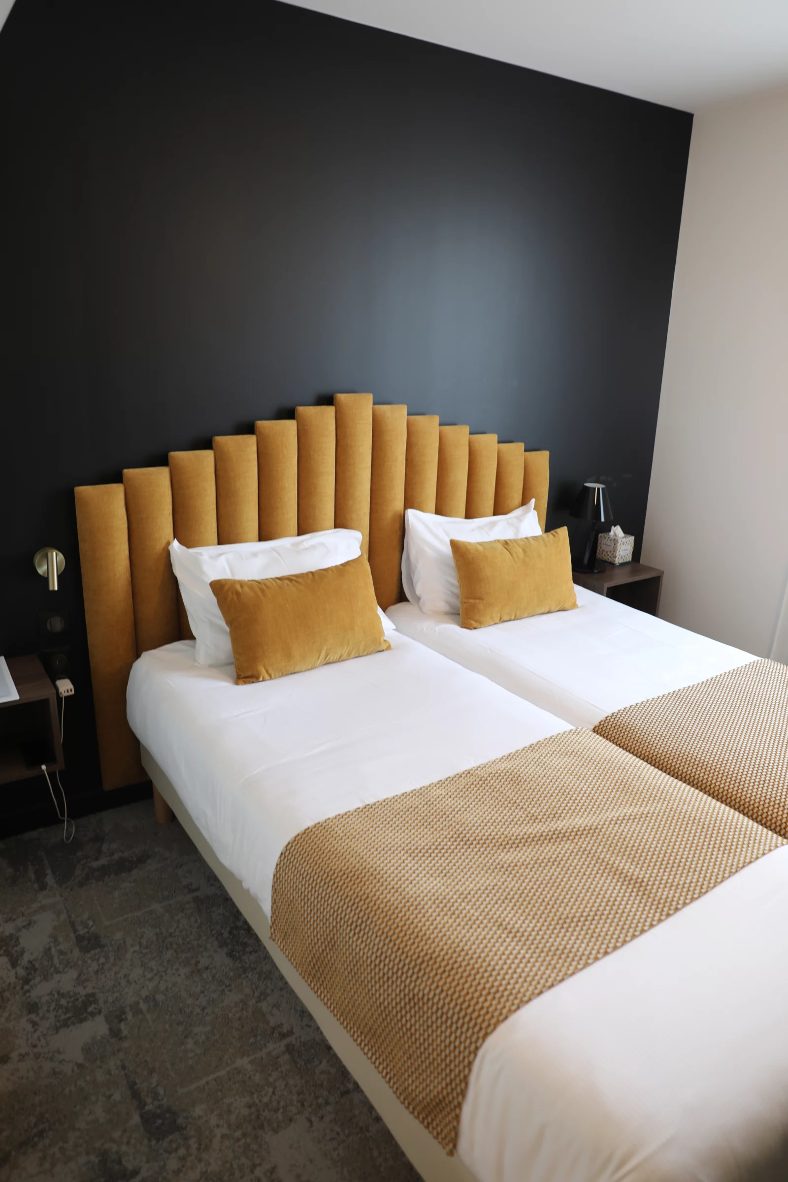 Kamer met twee bedden en geel hoofdbord in Hôtel Les Pins op Île d’Oléron
