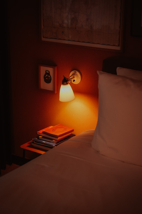 Leeslamp en boeken naast het bed bij Le Barn