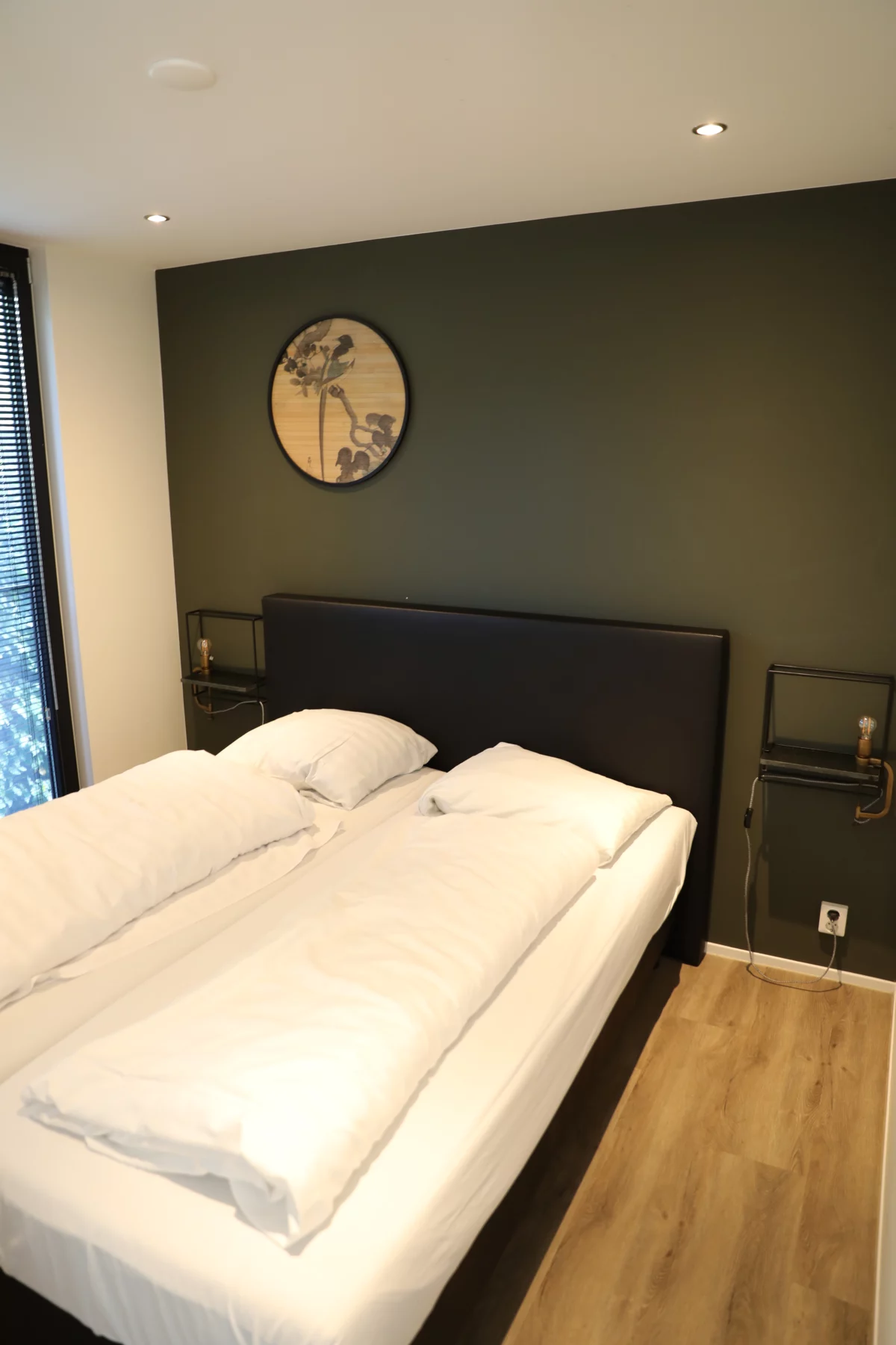 Slaapkamer met tweepersoonsbed en groene wand in een lodge op Soof Heuvelrug